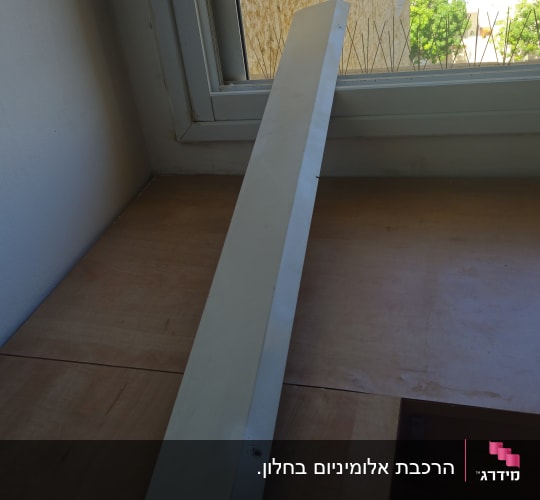 חלון עם פרופיל מתכת על שולחן עץ